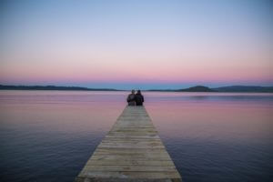 couple on dock at sunset lake rotorua new zealand