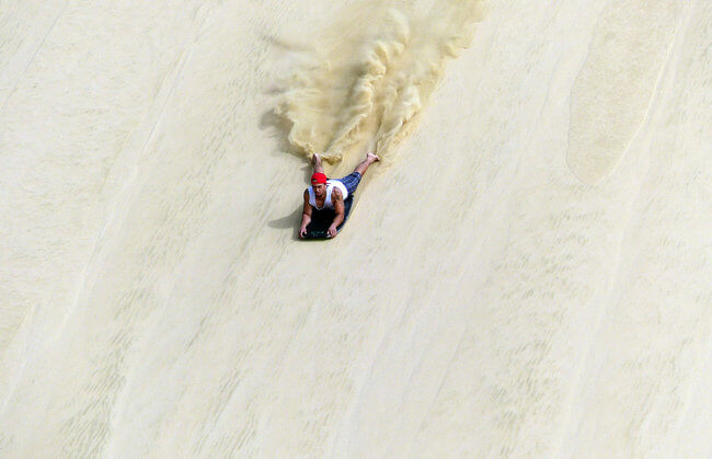 sand surfing down Te Paki Sand Dune New Zealand