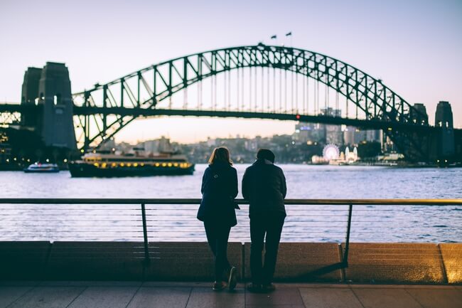 woman and man facing sydney harbour bridge dusk
