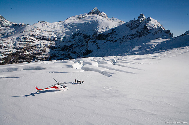 Helicopter landed on the top of the Franz Josef Glacier, with people hiking through the deep snow