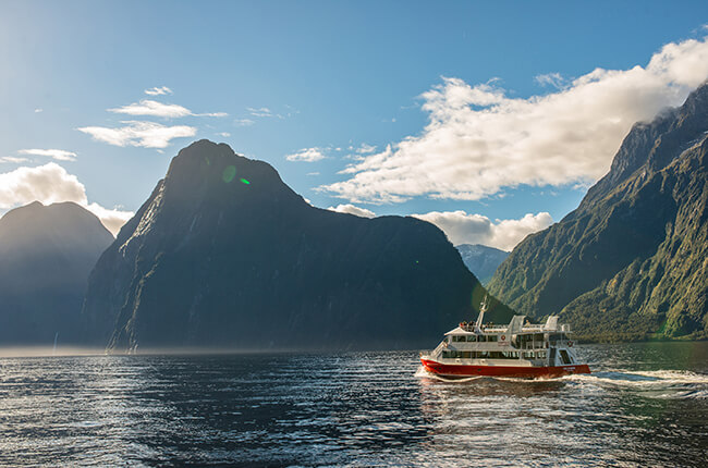 cruiseboat sailing along clear waters overlooking tall mountains