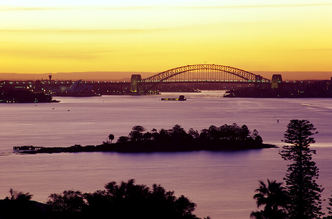 Sydney Harbour at sunset, featuring the Opera House and Harbour Bridge in the distance