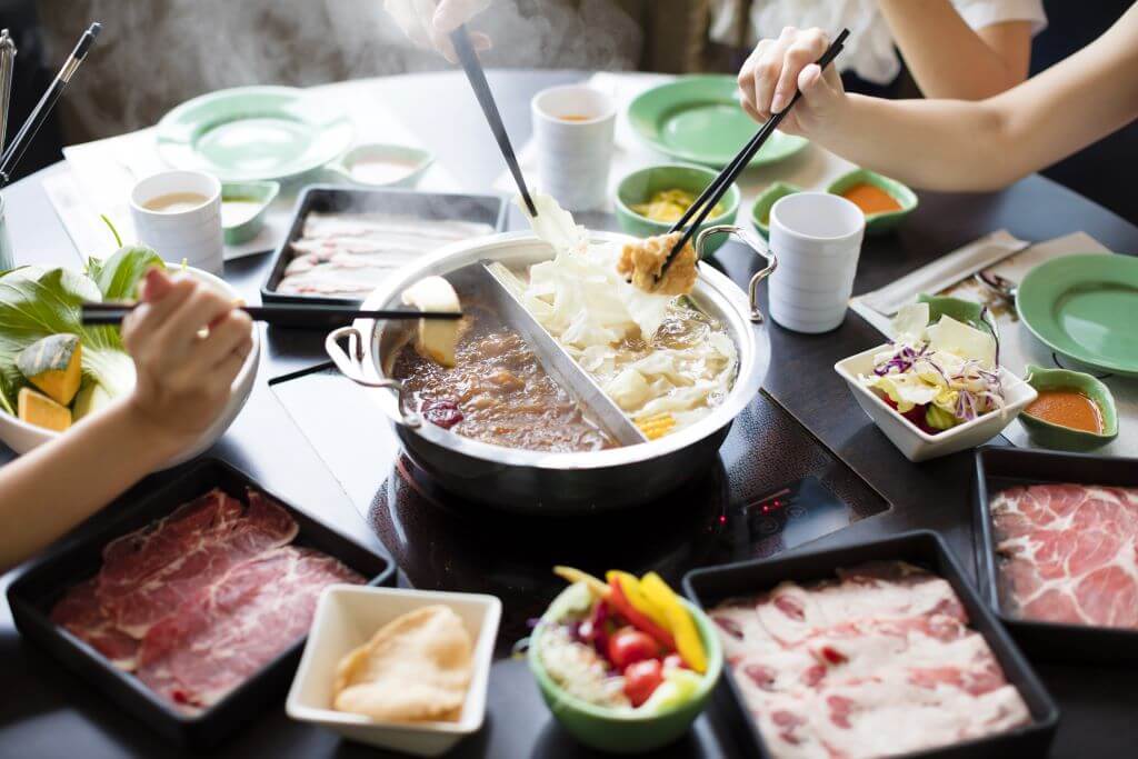 Japanese Shabu Shabu dinner with many plates and people using chopsticks