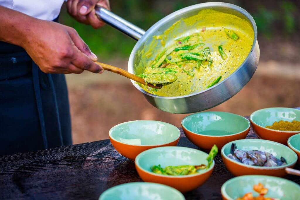 chef spooning into dish with other ingredients in bowls on table