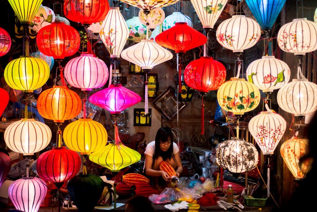 woman making lantern with many lanterns on display