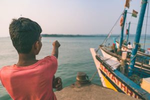 boy at harbour by fishing boat in Worli fishing village Mumbai India