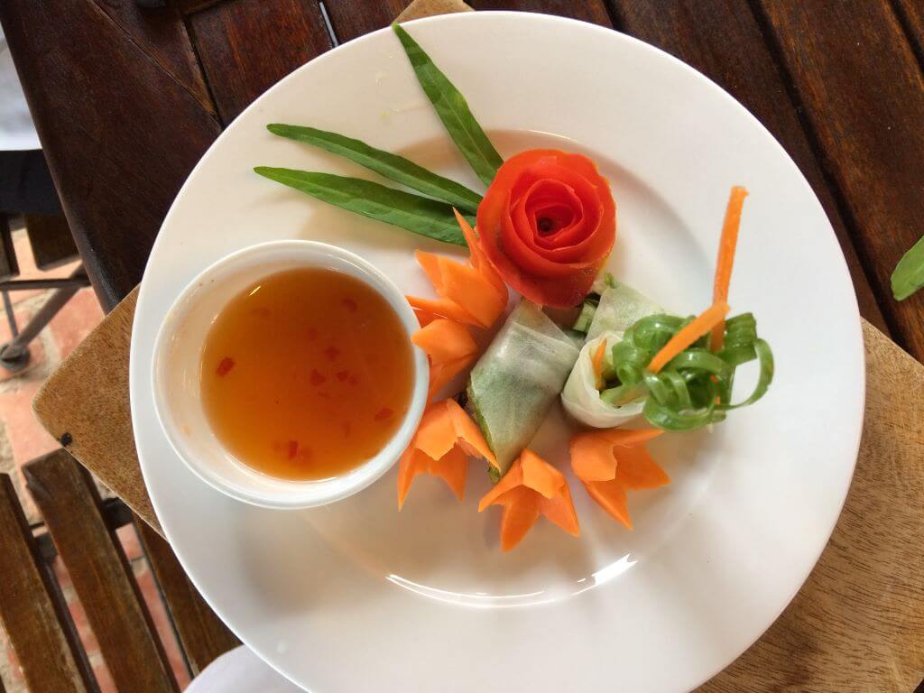 plate of vegetables crafted like flowers with pot of sauce