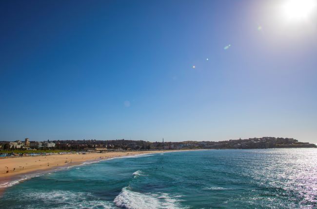Bondi beach with the sun shining and waves coming into the beach
