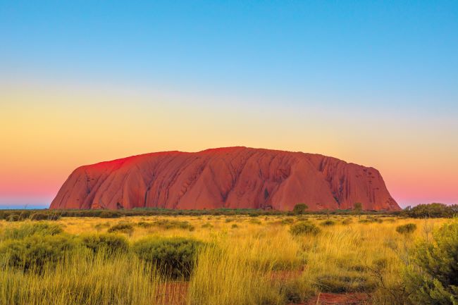 Uluru at sunset with changing colours in the background