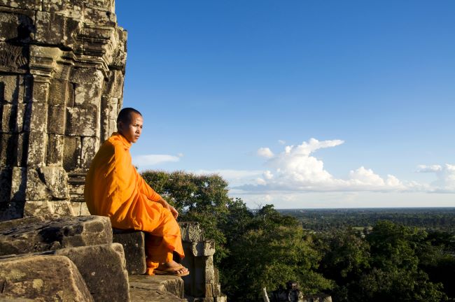 Buddhist Monk contemplating high up on the complex of Angkor Wat, Cambodia