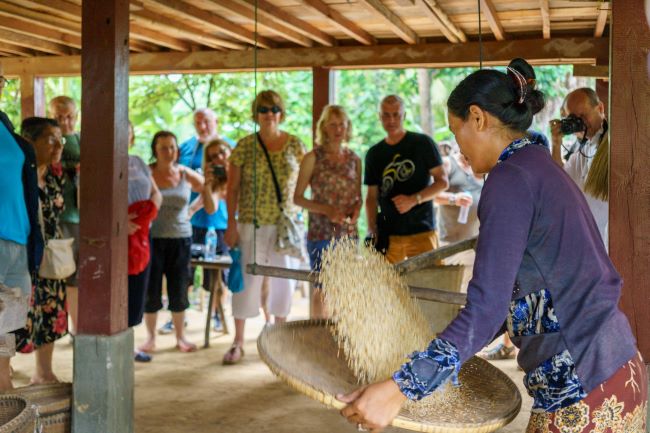 Local cambodian lady showing tourists how rice grain is sifted