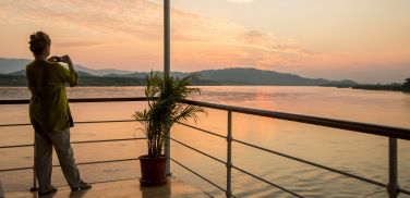 Lady taking pictures of the mighty Mekong River at sunset of the