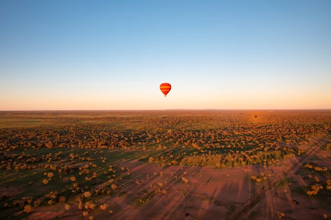 Hot Air Balloon floating high in the sky above the vast red outback of the red centre, near Alice Springs
