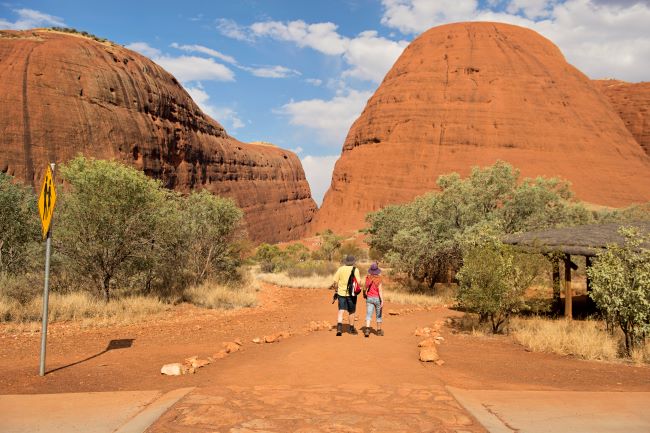 Couple walking towards Walpa Gorge at Kata Tjuta also known as The Olgas, in Australia's red centre