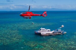 Helicopter flying over Great Barrier Reef with Sunlover pontoon in the baclground