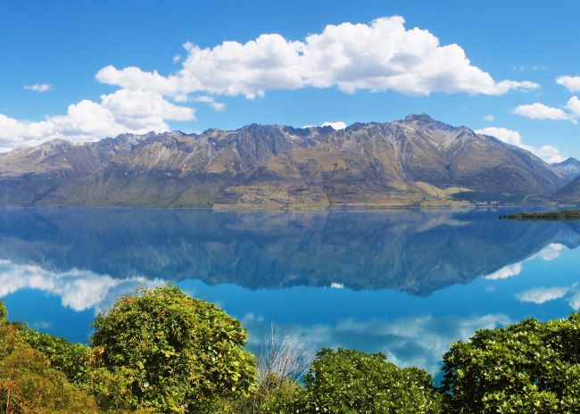 View of the Southern Alps, New Zealand with the reflection mirrored in the clear blue waters of Lake Wakatipu 