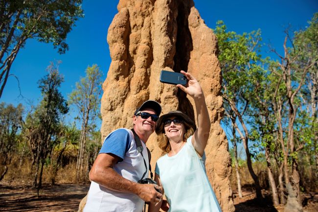 Couple taking a selfie in front of a large termite mound in Litchfield National Park, near Darwin in Australia's Top End