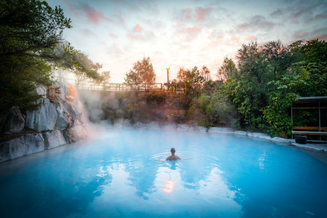 Lady swimming in the naturally heated geothermal pools at Wairakei Terraces, Rotorua, New Zealand