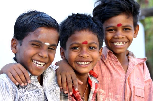 Three young laughing Indian boys smiling at the camera