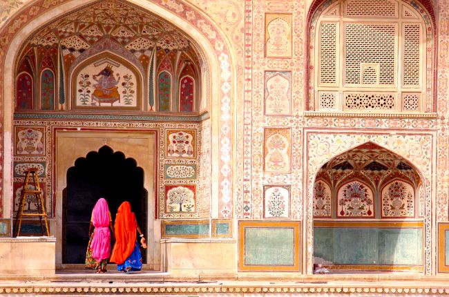 Two Indian ladies walking through an ornate door at Amber Fort, Jaipur India