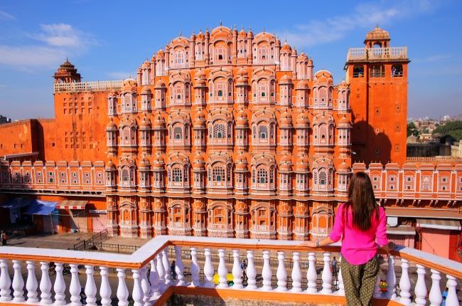 Lady in bright pink standing in front of Hawa Mahal Palace in Jaipur