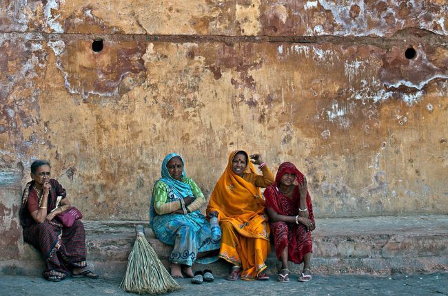 Three Indian ladies in traditional dress sat against a wall in Jaipur