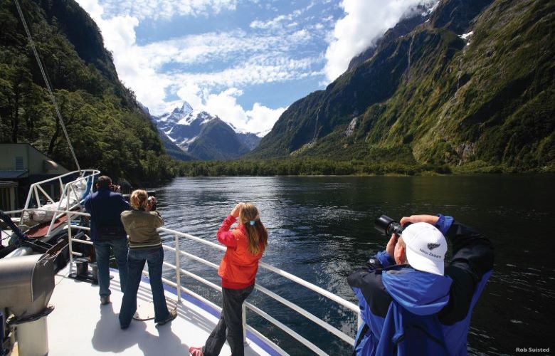 Group of people taking pictures from a boat on Milford Sound in New Zealand