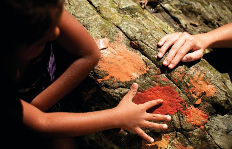 Aboriginal girl and lady looking at rock painting