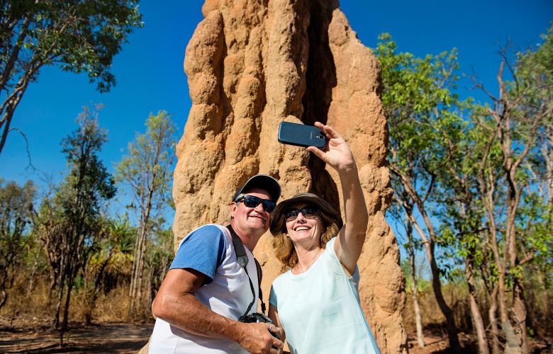 Couple taking a photo in front of large termite mound